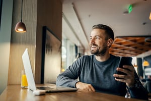 smiling man talking on the phone and working on a laptop 