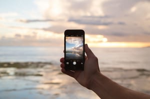 A person taking a photo of the sunset with their phone
