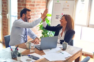 Male and female coworkers high-fiving in the office