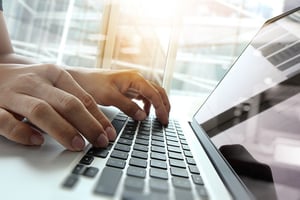Close-up view of a person working on a laptop 